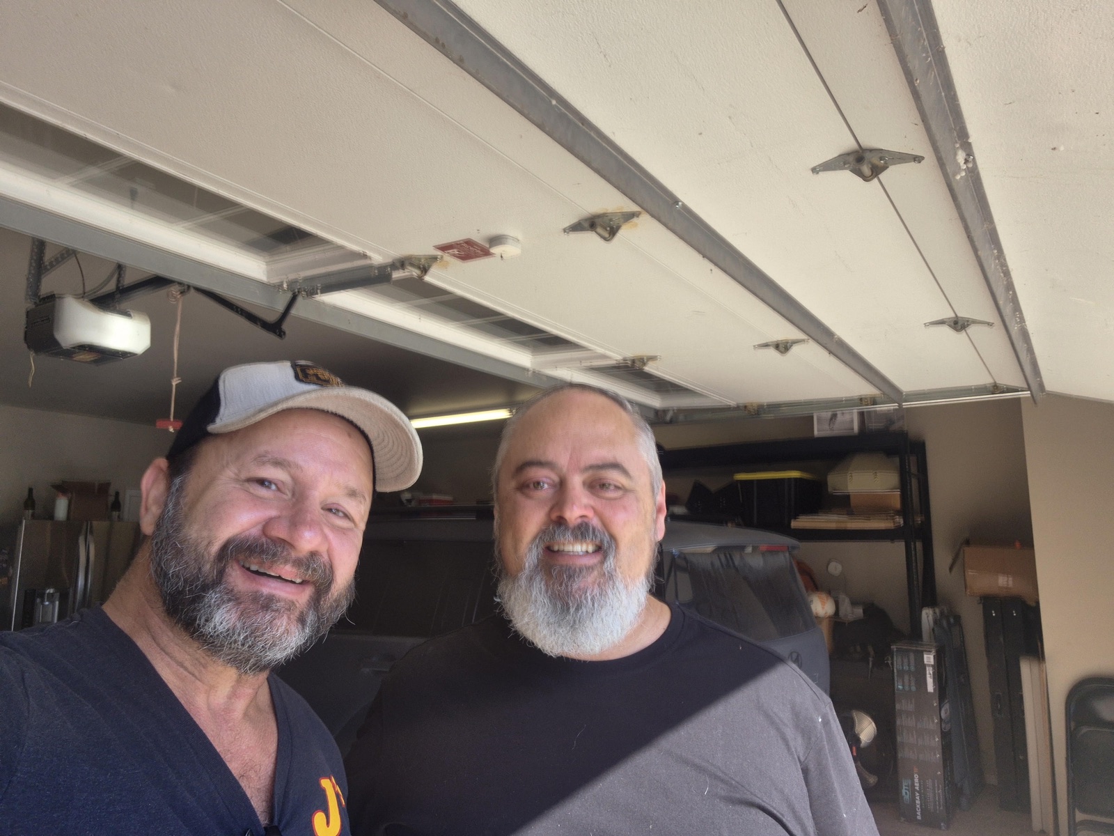 Two J's Overhead Door team members smiling in a residential garage in Sand Springs, Oklahoma